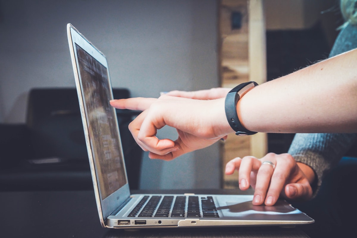 Two people looking at a laptop together, one pointing at something on the screen