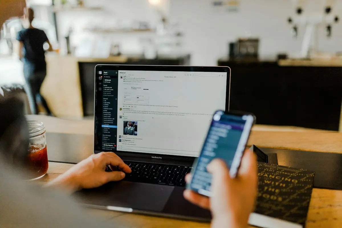 A person using a laptop and a phone chat app at the same time