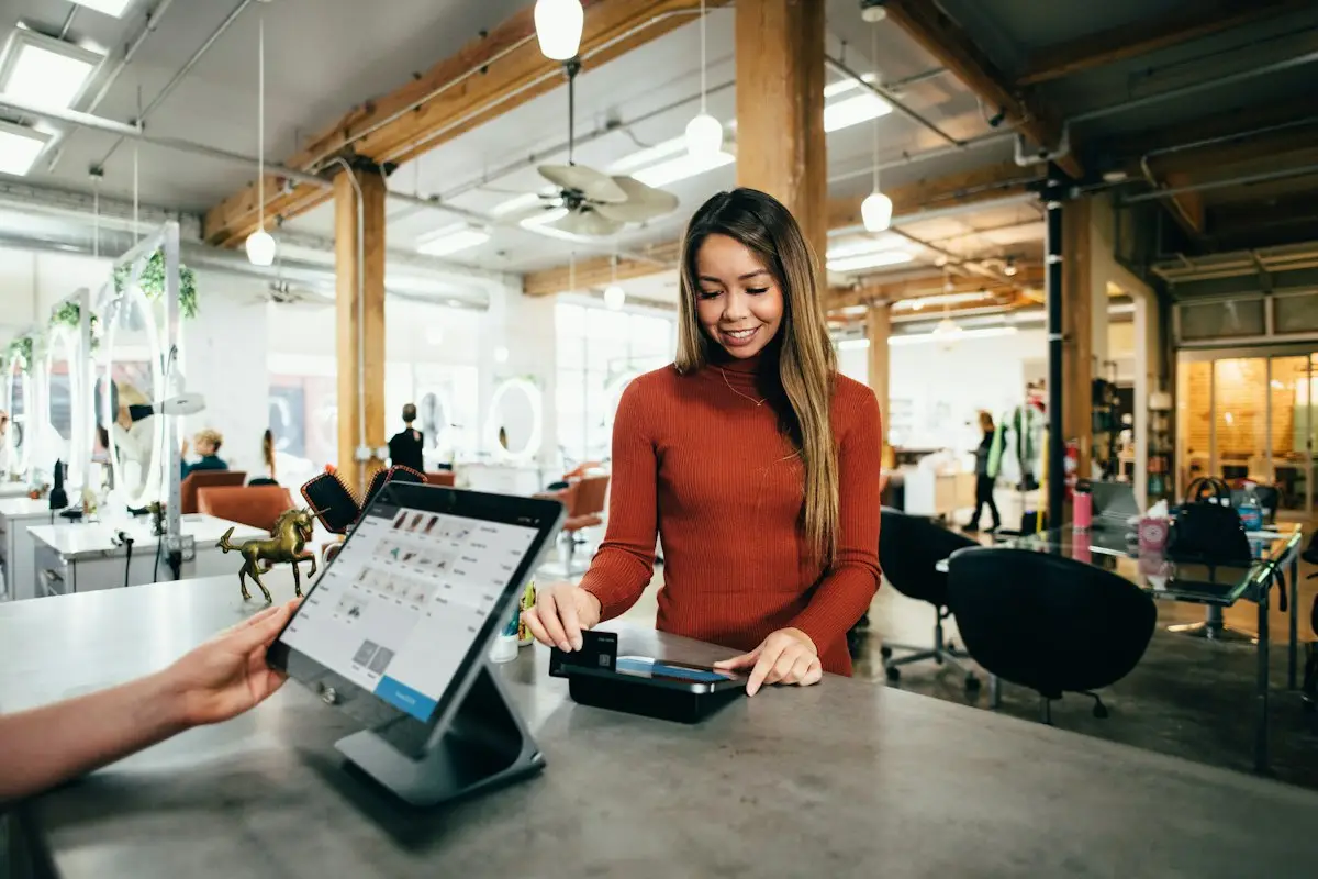 A shop owner taking an order on a tablet at the counter
