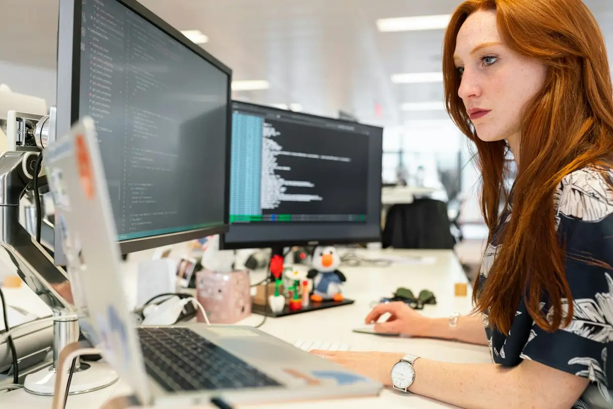 A developer at a desk with code on two monitors