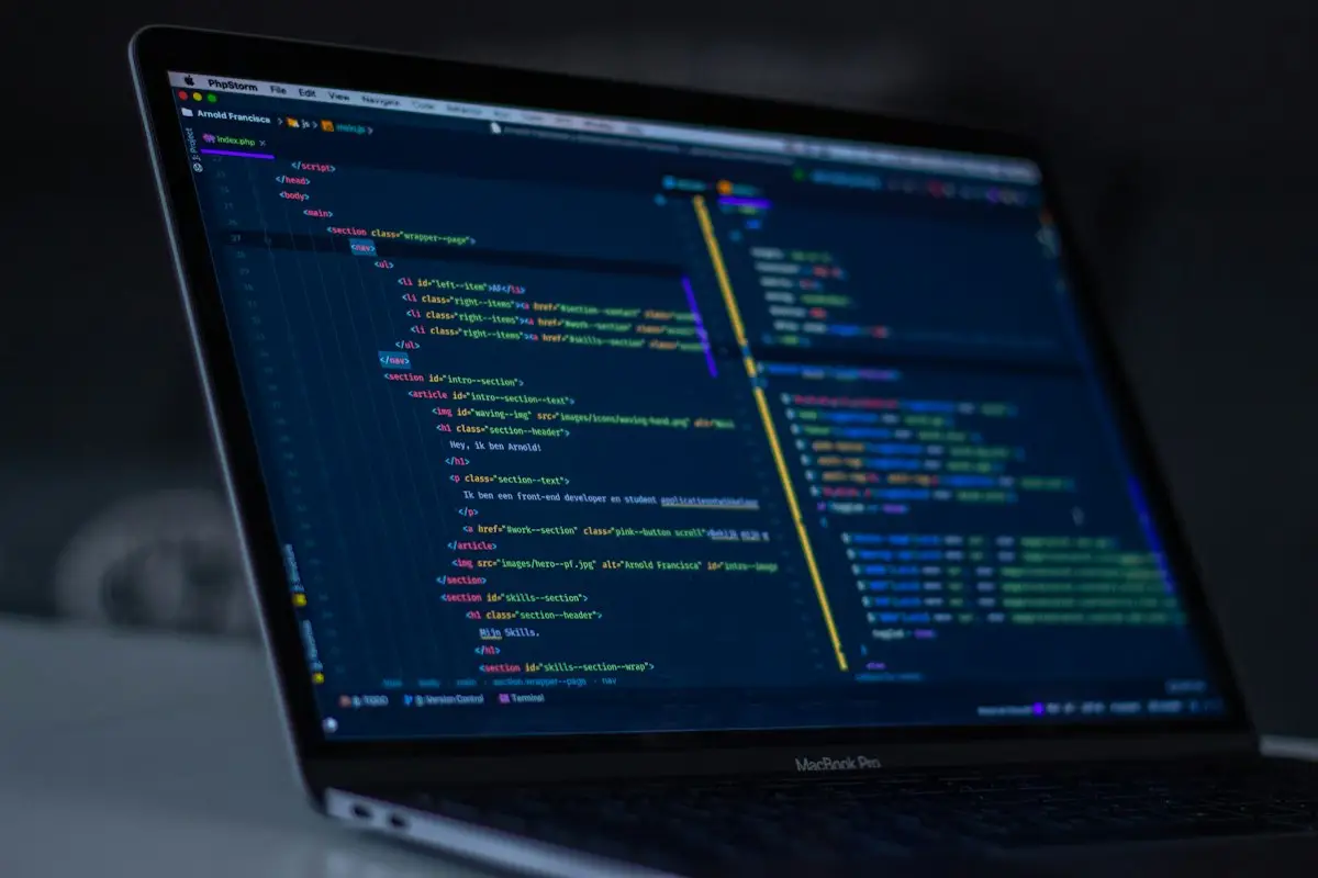 A laptop with code on screen in a dark room