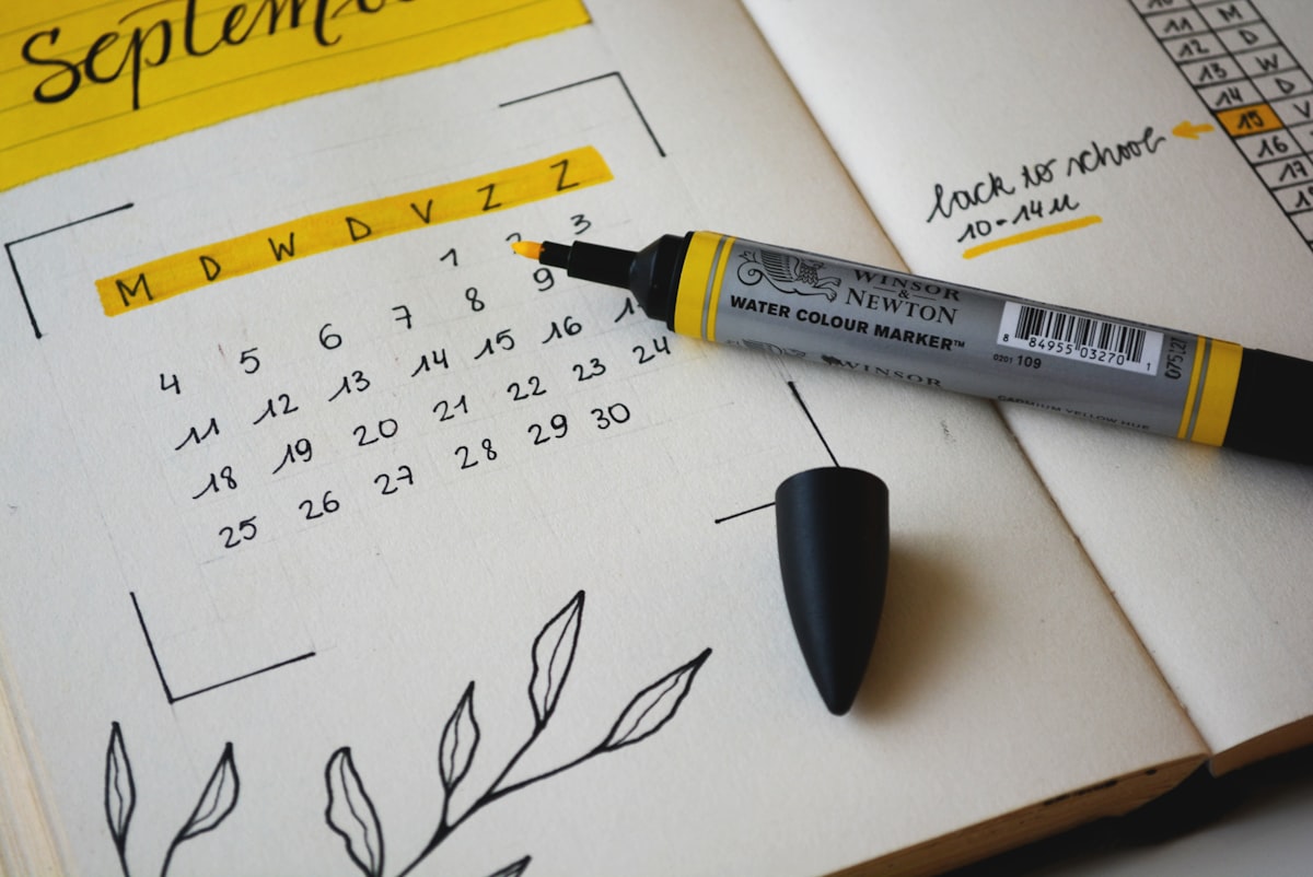 Hand-drawn September calendar in a bullet journal with a yellow marker pen resting on the page