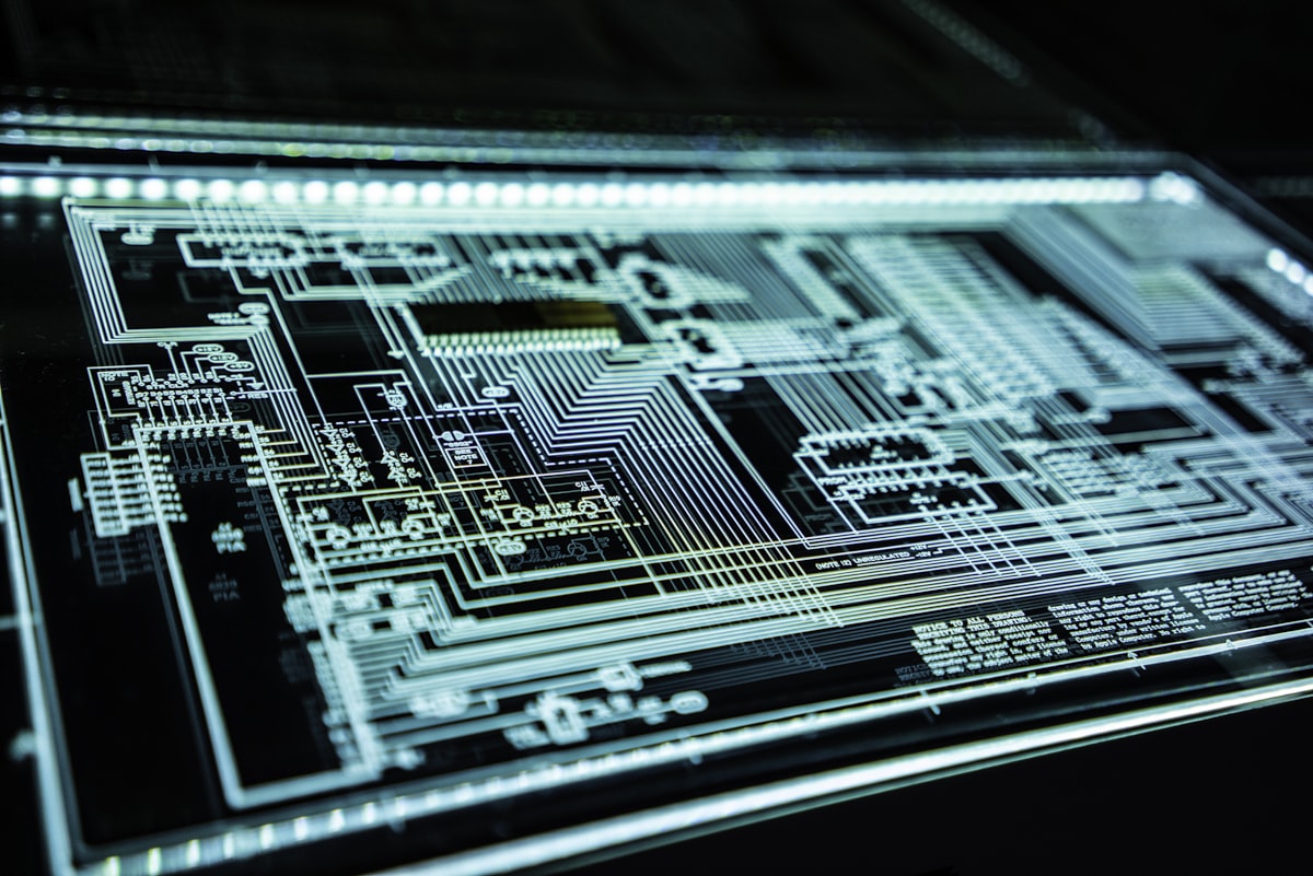 Illuminated circuit board schematic glowing pale blue on a dark surface
