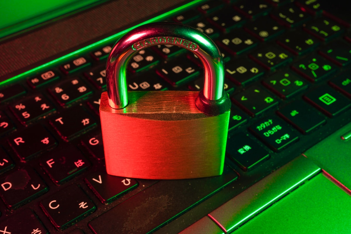 Brass padlock standing on a laptop keyboard lit with red and green light