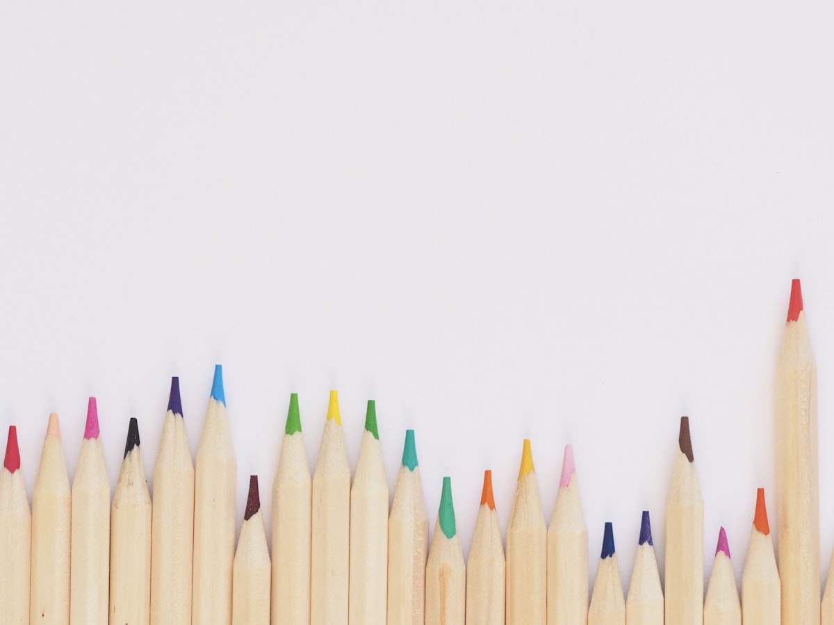 A row of coloured pencils with their tips in a rainbow of colours against a white background