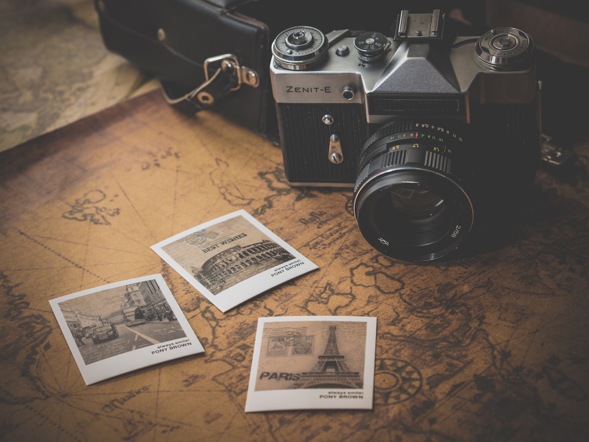 A vintage film camera and three printed photographs laid on an old map