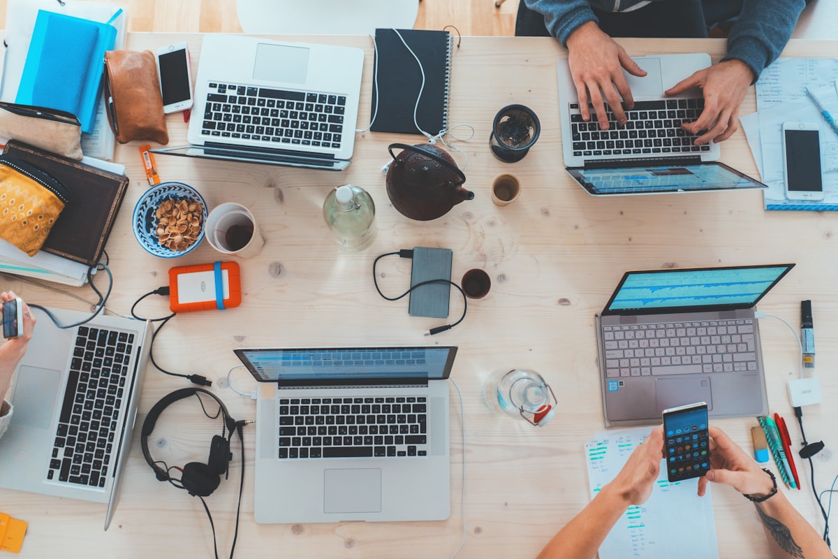Overhead view of a team working together on laptops and phones at a wooden table