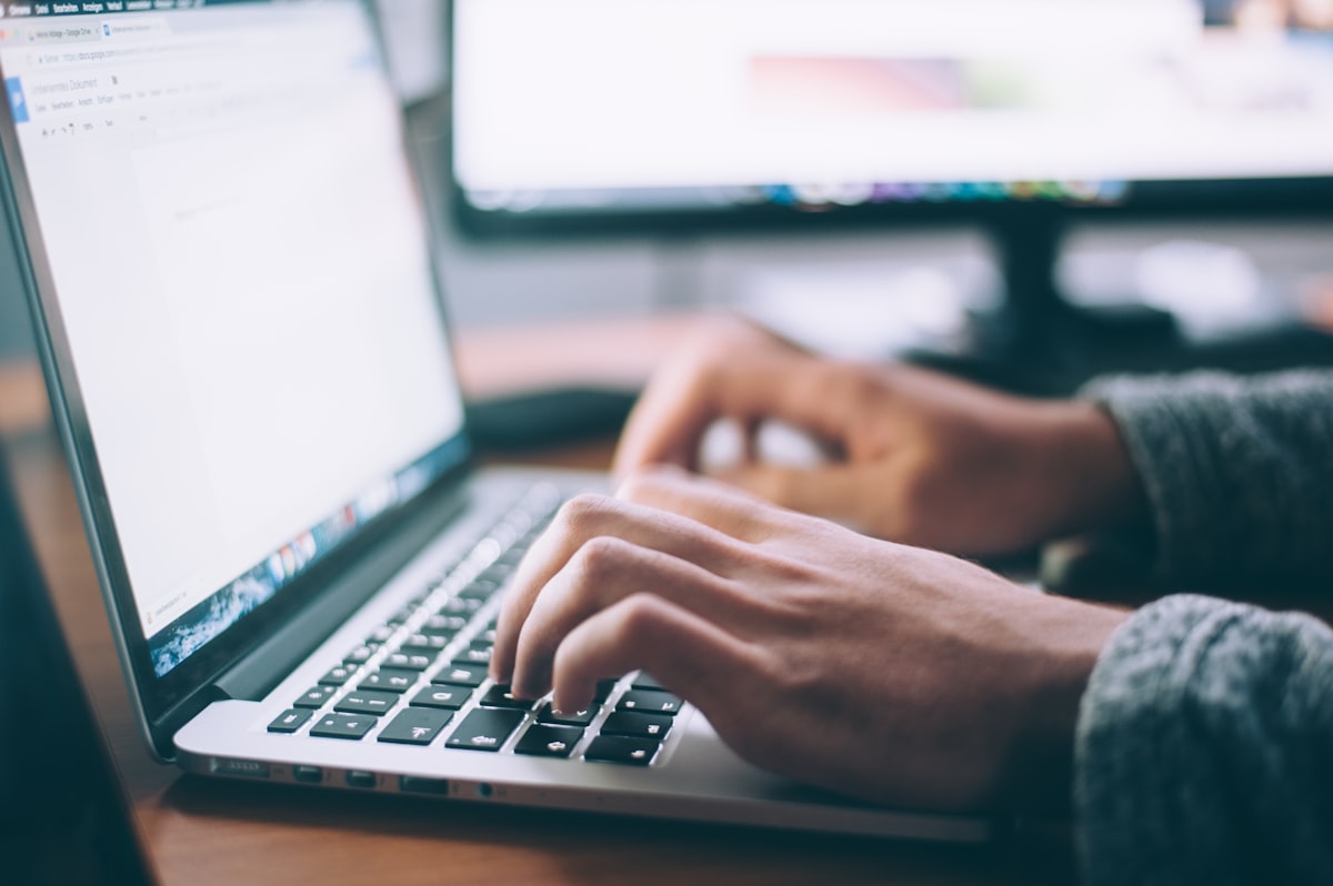 Hands typing on a laptop keyboard with a document open on screen